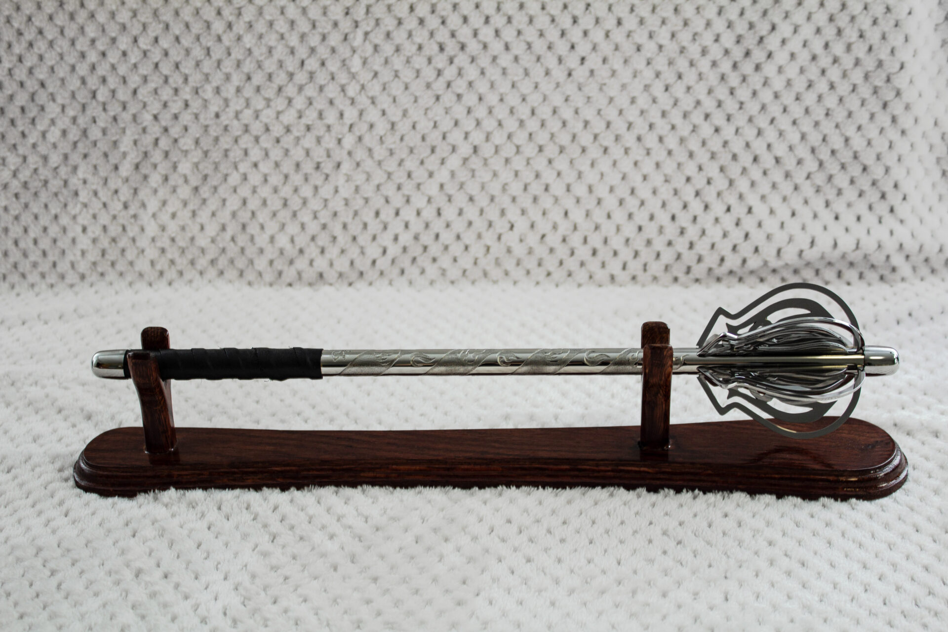 Full side profile of a pernach on a wooden stand, with openwork flanges and black wrapped grip