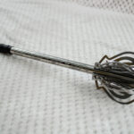 Pernach laid on pale fabric, showing its openwork head, patterned shaft and black wrapped grip