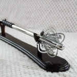 Pernach with openwork head and smooth shaft on a dark wooden display stand, angled view