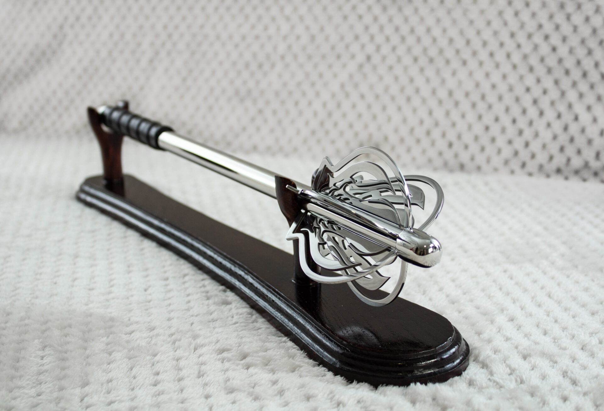 Pernach with openwork head and smooth shaft on a dark wooden display stand, angled view