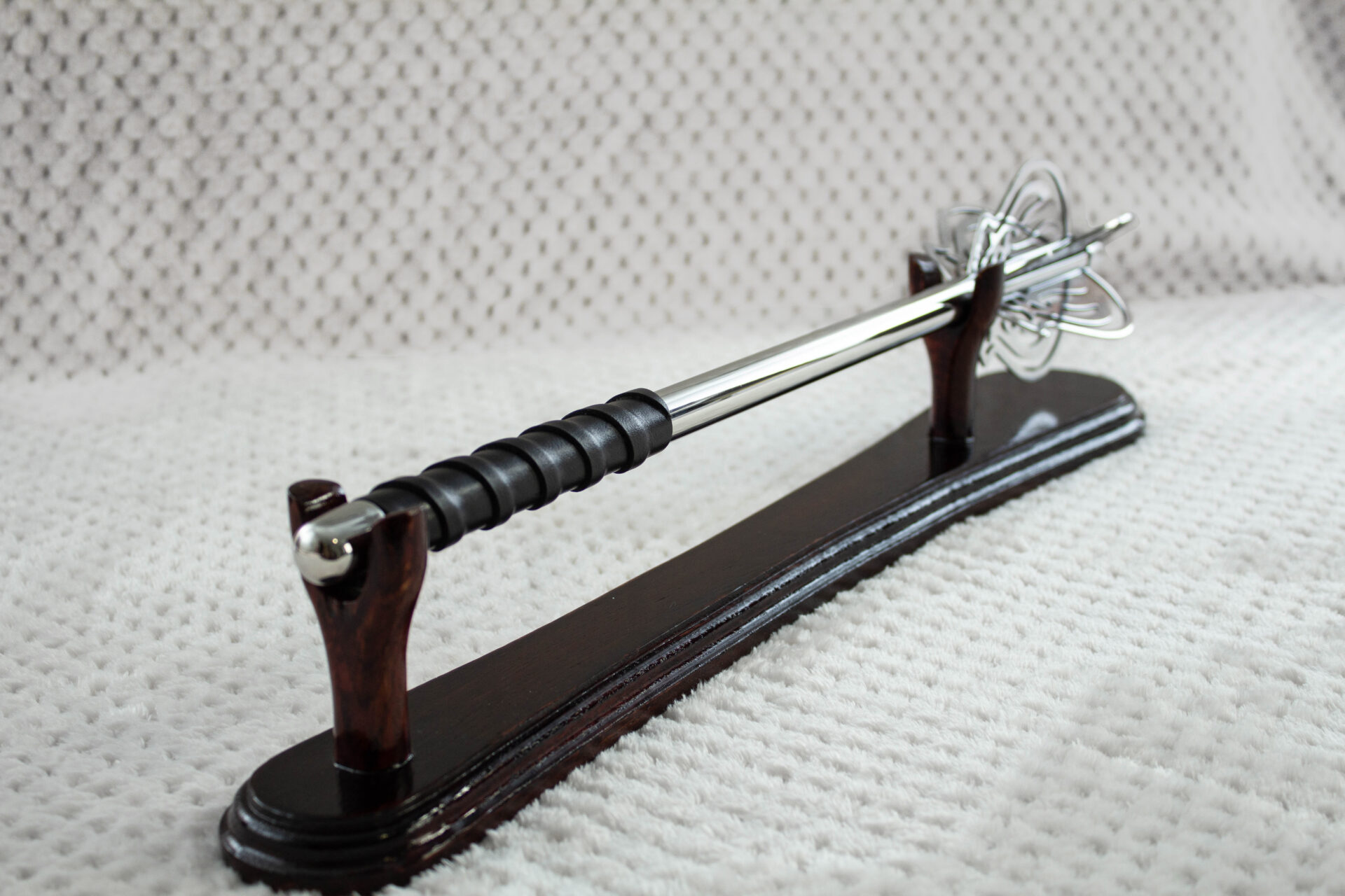 Pernach on a wooden stand viewed from the black wrapped grip along its smooth shaft