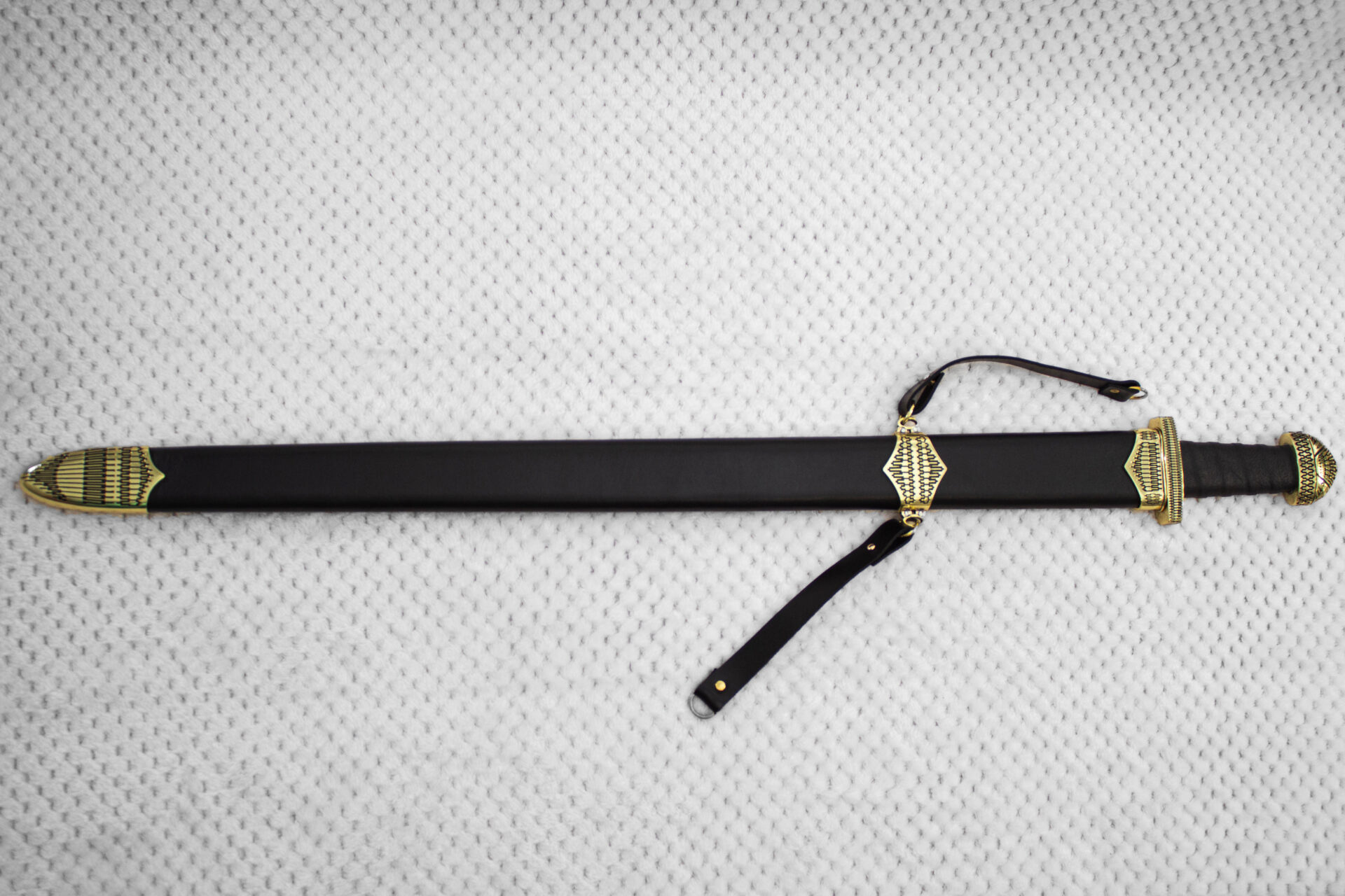 Sviatoslav's sword sheathed in black, with geometric patterns on the tip, carrying-strap fitting and hilt