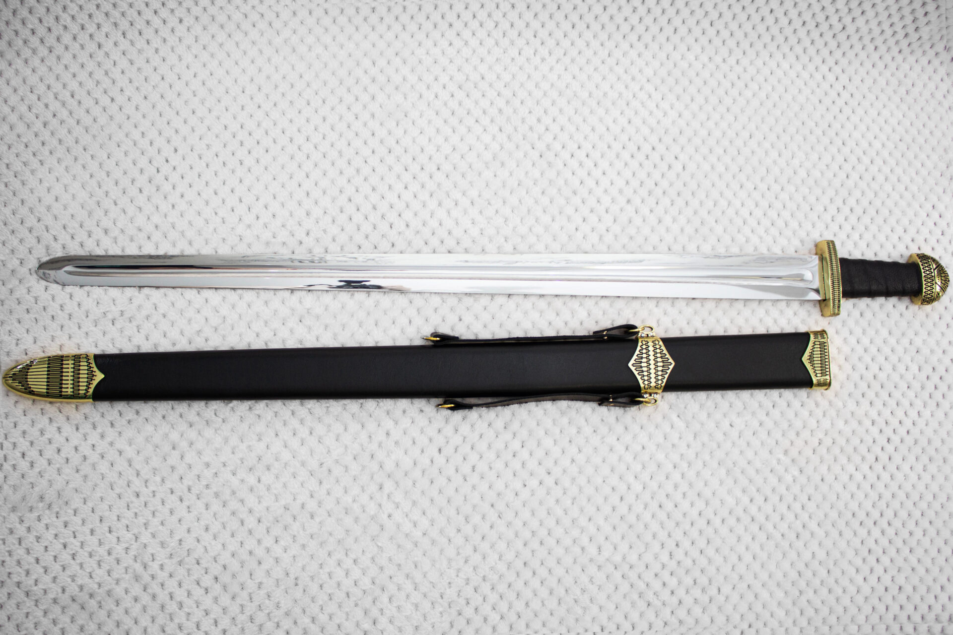 Full-length Sviatoslav's sword beside its black scabbard with patterned fittings and carrying straps