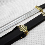 Sviatoslav's sword beside a black scabbard, showing the blade, wrapped grip and patterned fittings