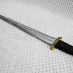 Angled view along the fullered blade of Sviatoslav's sword from its black grip and patterned guard