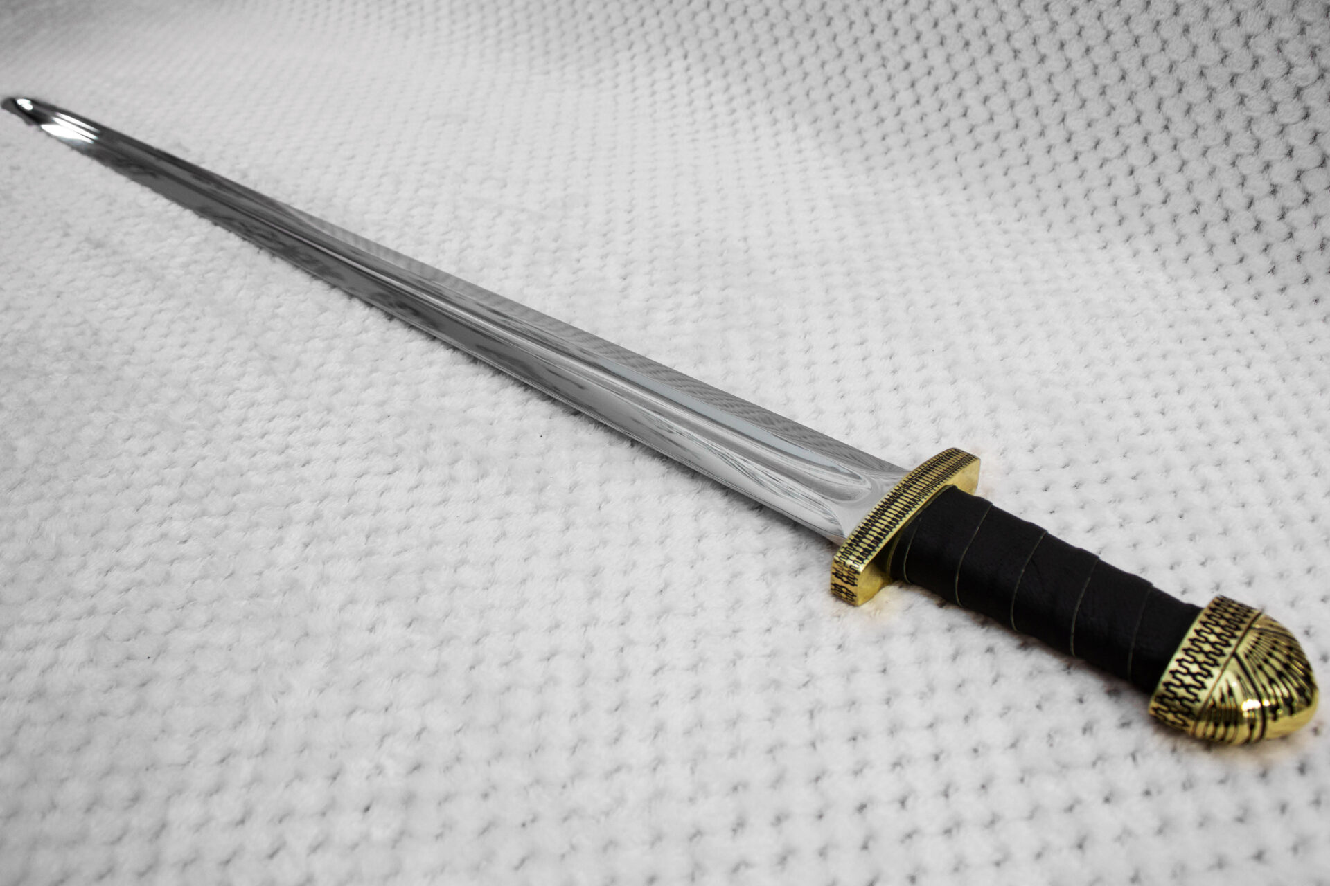 Angled view along the fullered blade of Sviatoslav's sword from its black grip and patterned guard