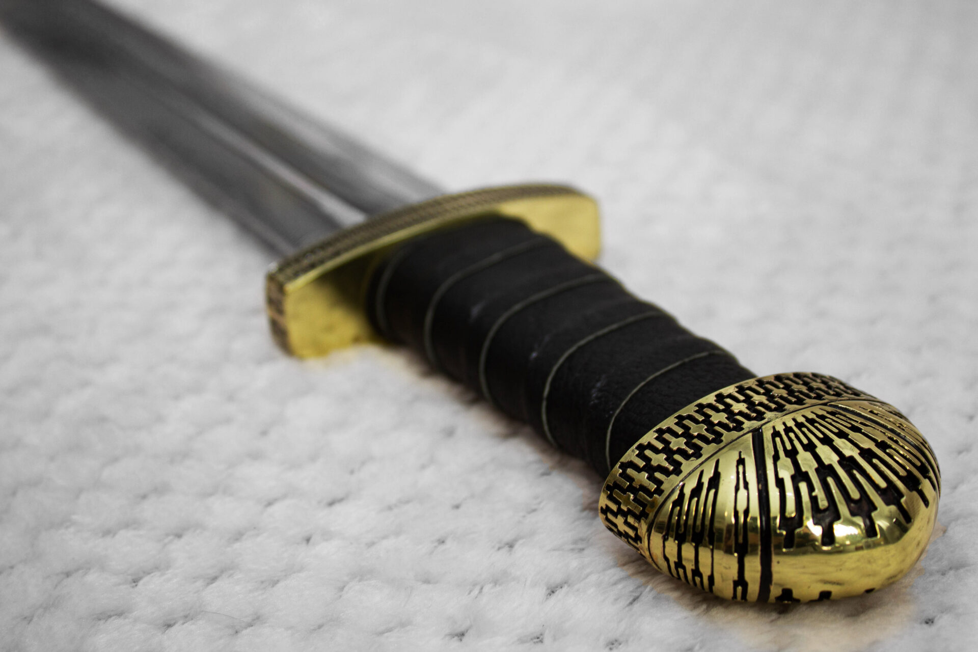 Close-up of the black wrapped grip, patterned pommel and guard of Sviatoslav's sword