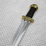Sviatoslav's sword hilt and blade base, showing a black grip, patterned guard and deep central fuller