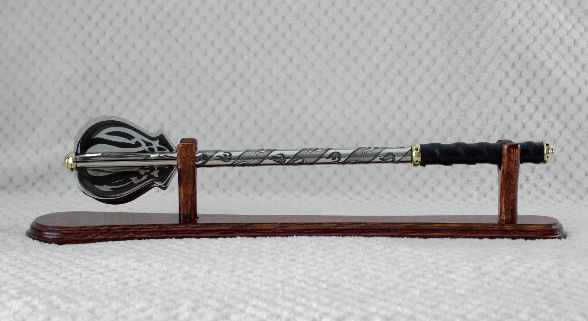 Side profile of a pernach with dark patterns on its flanges and shaft, displayed on a wooden stand