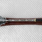 Overhead view of a pernach on a wooden stand, showing its patterned head and shaft and black grip