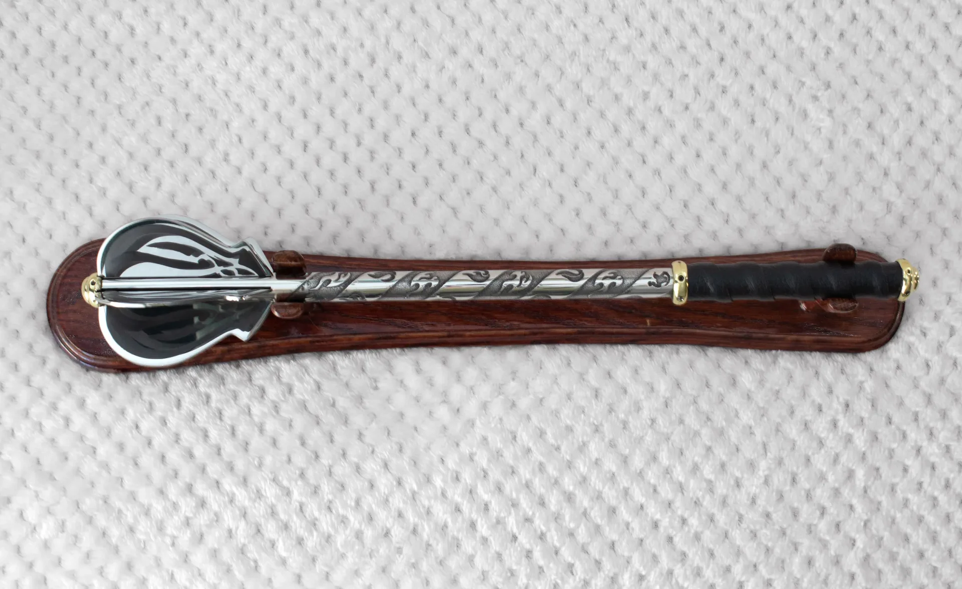 Overhead view of a pernach on a wooden stand, showing its patterned head and shaft and black grip