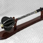 Pernach on a wooden display stand, showing its flanged head, patterned shaft and black grip