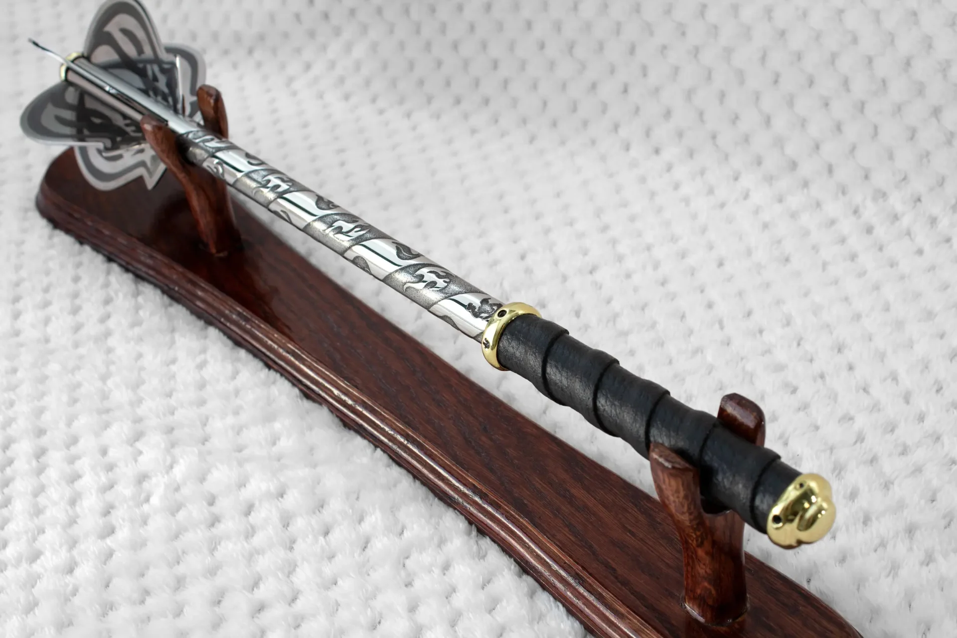Pernach on a wooden stand viewed from the black grip along its patterned shaft toward the flanged head