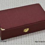 Closed burgundy presentation box for a gift scroll, with decorated corner fittings and a clasp