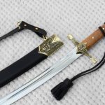 SiCh-KzO saber with brown grip and decorated guard beside its black scabbard
