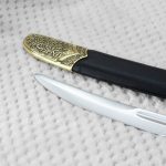 Close-up of the SiCh-KzO blade tip beside the decorated black scabbard tip
