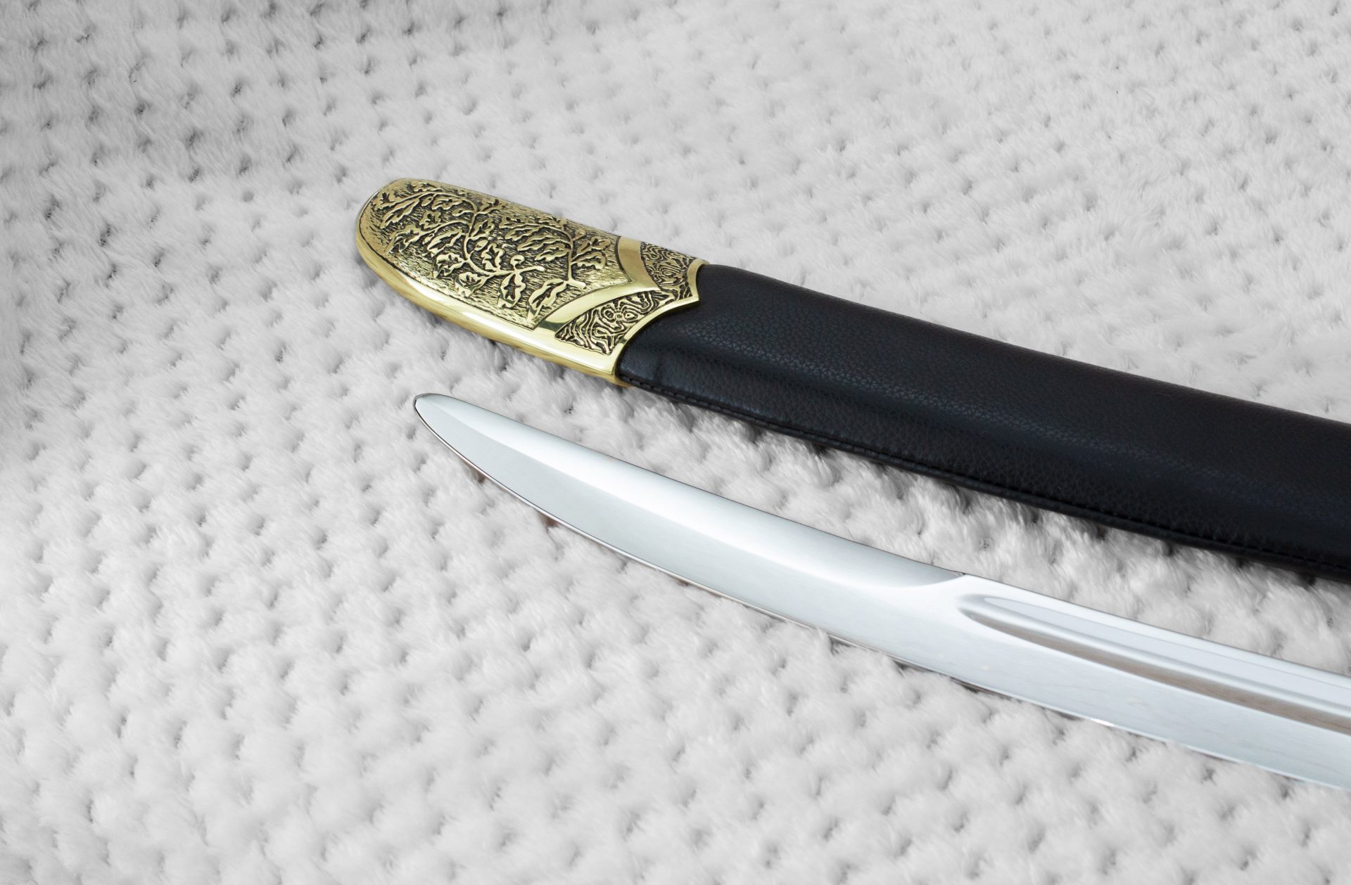 Close-up of the SiCh-KzO blade tip beside the decorated black scabbard tip