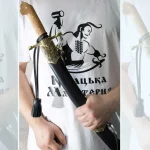 SiCh-KzO saber held in its black scabbard, showing the brown grip and decorated throat fitting