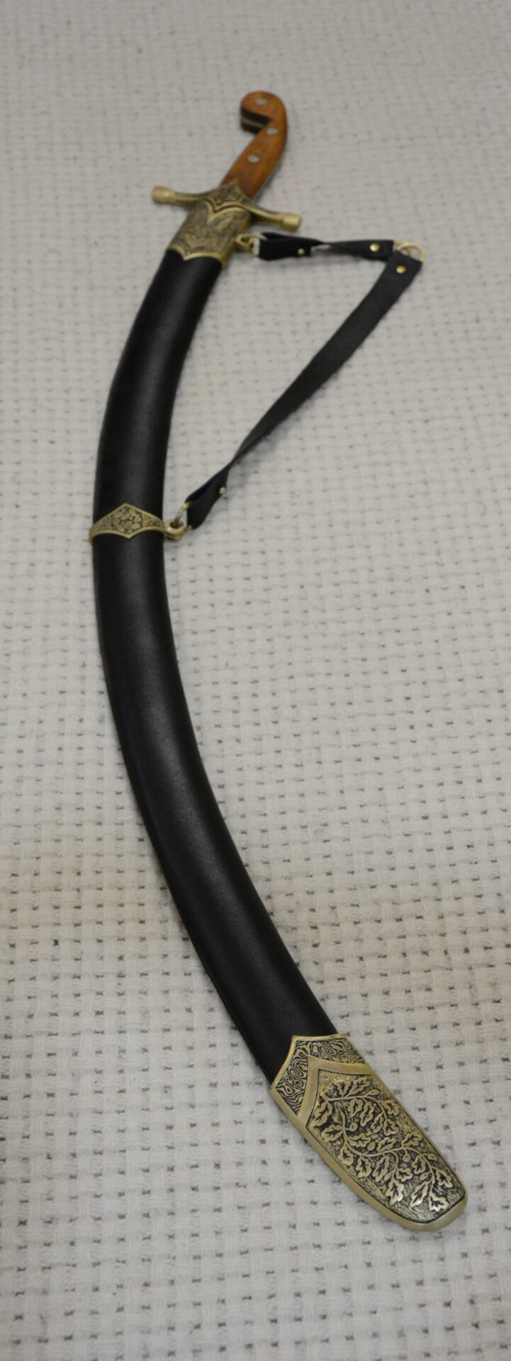 SiCh-Sh saber in its black scabbard, viewed along the suspension strap toward the brown grip