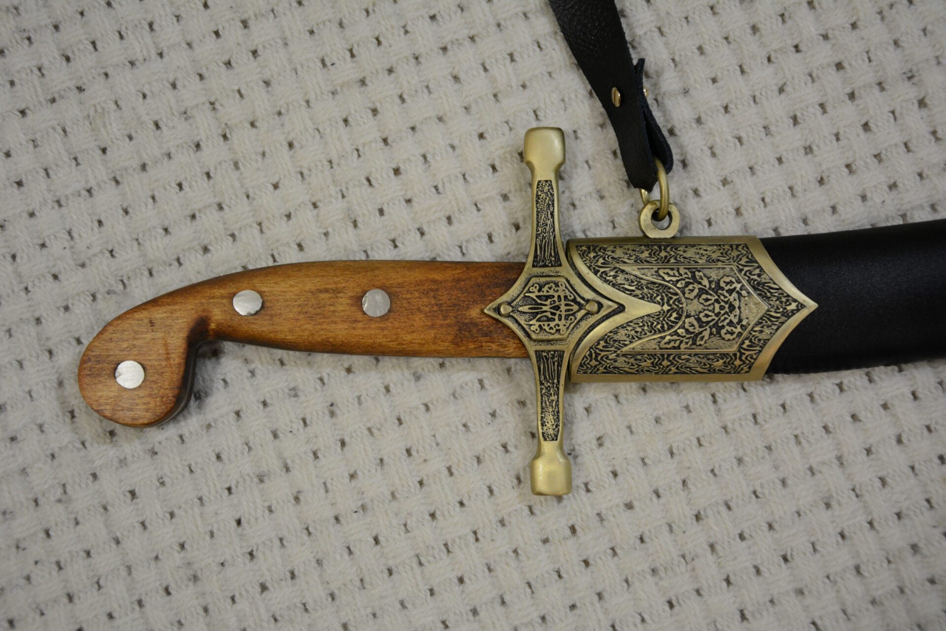 Close-up of the SiCh-Sh brown grip, decorated crossguard and scabbard throat