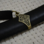 Close-up of the decorated suspension band and strap ring on the black SiCh-Sh scabbard