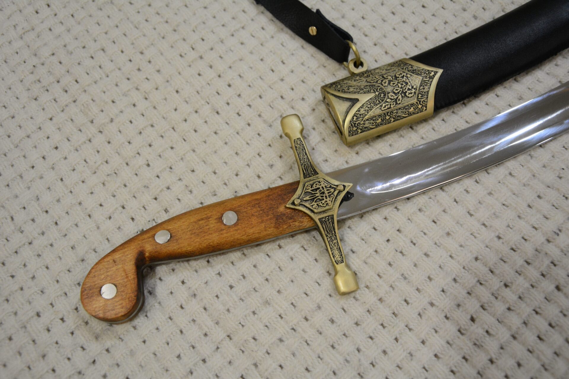 Close-up of the unsheathed SiCh-Sh hilt and blade beside the decorated scabbard throat