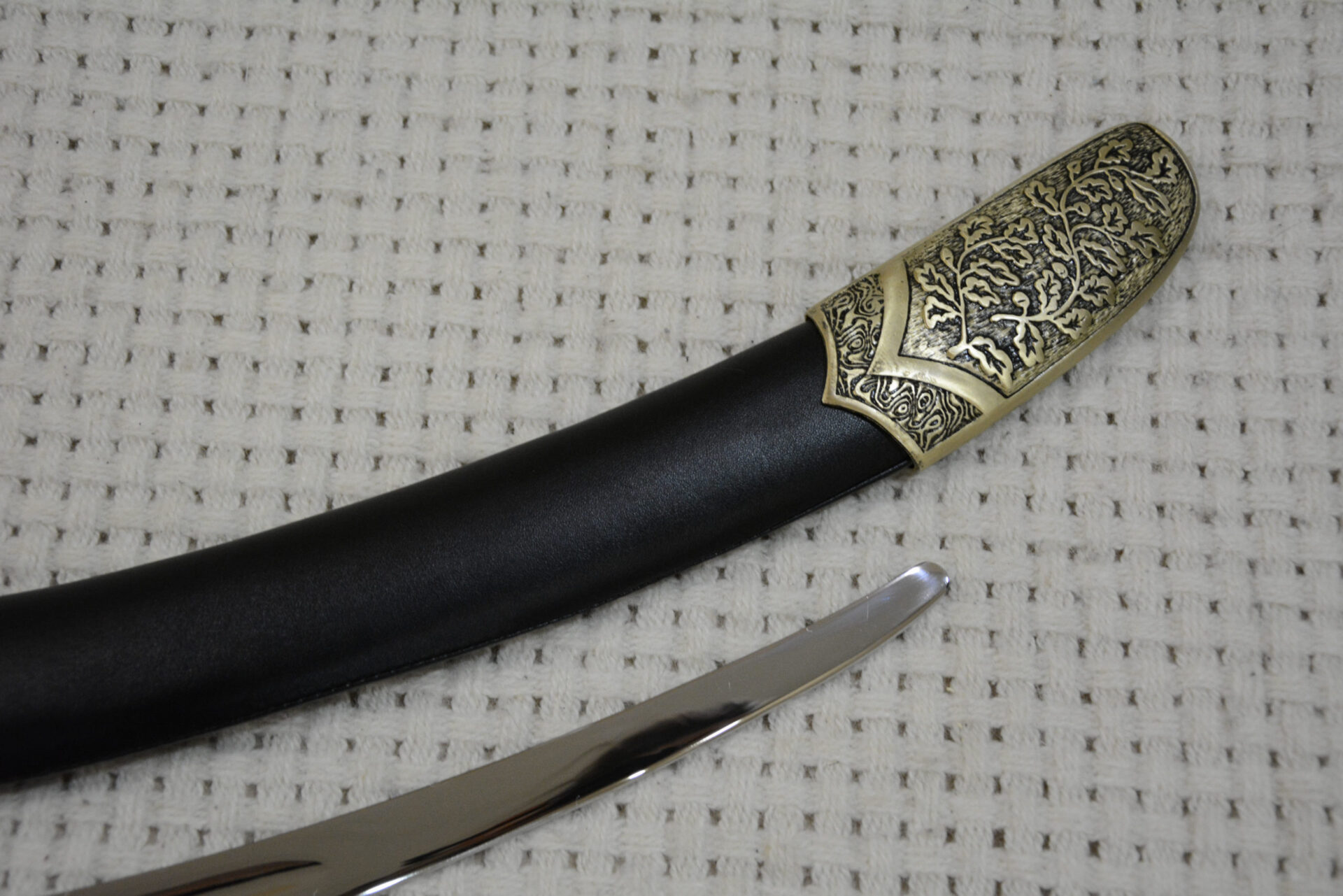 Decorated SiCh-Sh scabbard tip beside the exposed blade tip, close-up at an angle