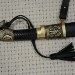 Top view of the Cossack shashka's black grooved grip and trident-decorated scabbard fitting
