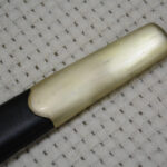 Smooth rounded metal tip of the Cossack shashka's black scabbard, shown close up