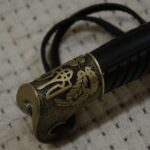 Trident and leafy ornament on the Cossack shashka's pommel beside the black grooved grip