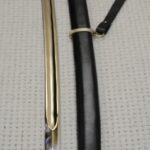 View from the blade-tip end along the Cossack shashka and black scabbard toward the hilt and tassel