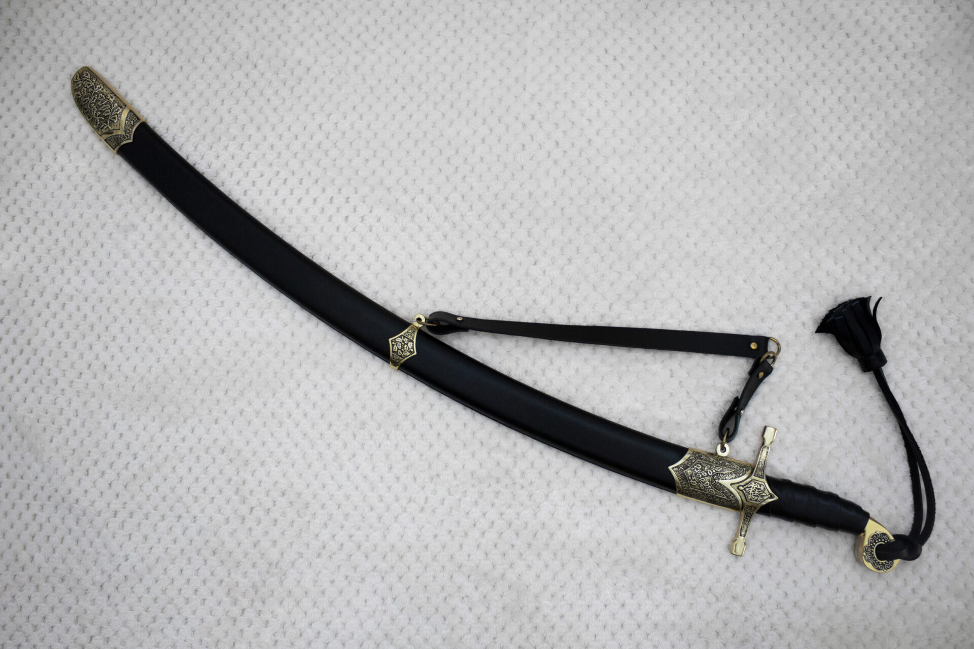 SiCh-Hetman saber in a curved black scabbard with a decorated tip and carrying strap, diagonal view