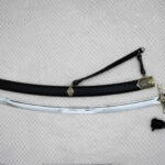 Unsheathed SiCh-Hetman saber laid beside its black scabbard with patterned fittings and carrying strap