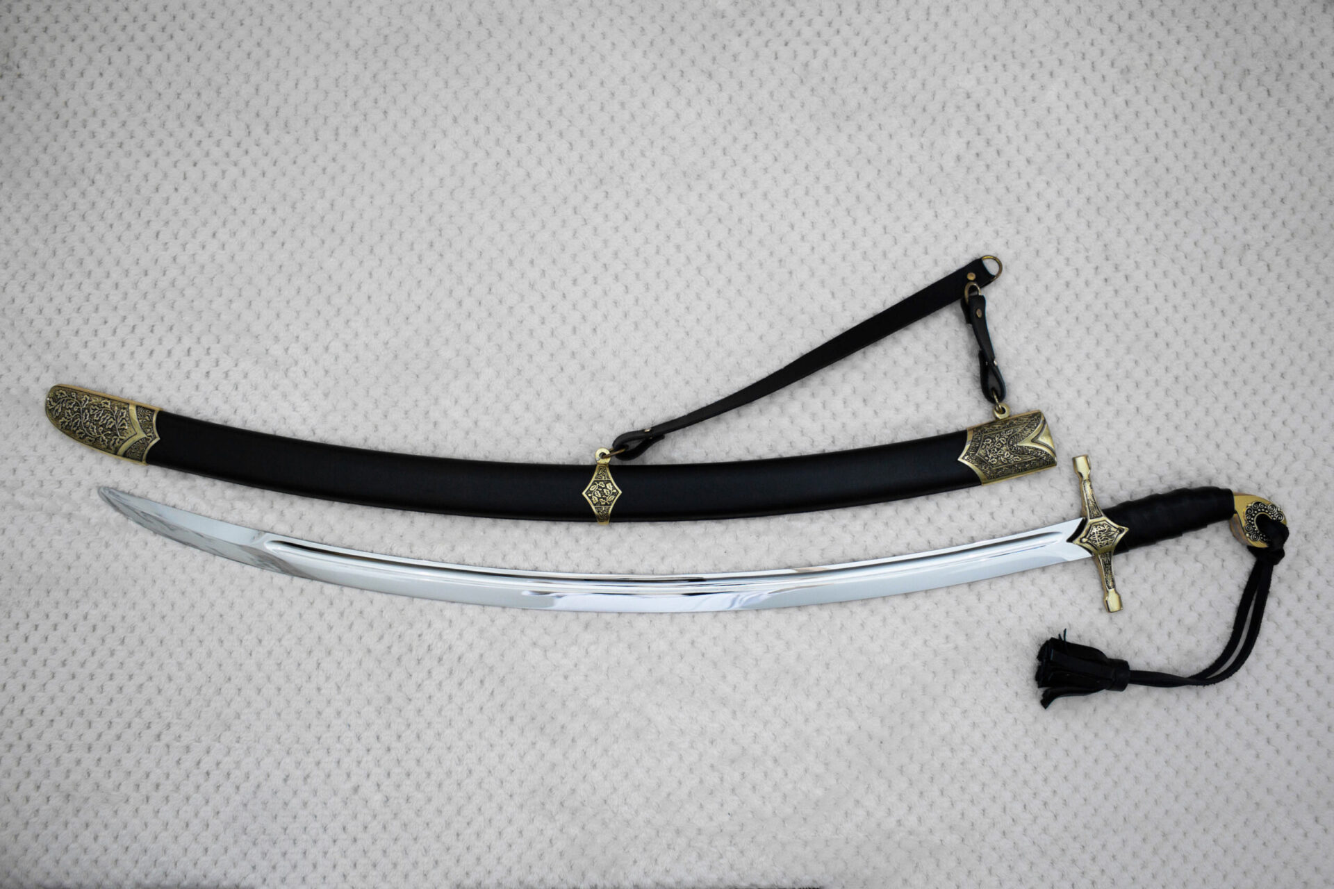 Unsheathed SiCh-Hetman saber laid beside its black scabbard with patterned fittings and carrying strap