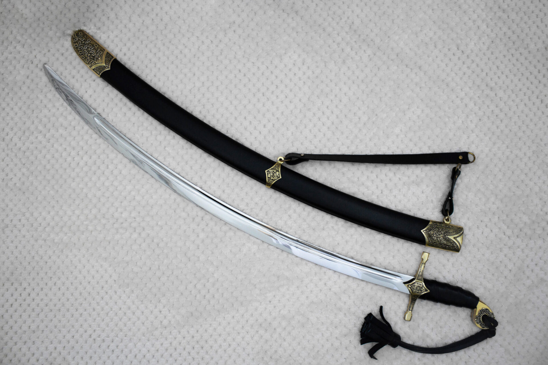 Curved SiCh-Hetman blade beside its black scabbard, showing the patterned scabbard tip and carrying strap