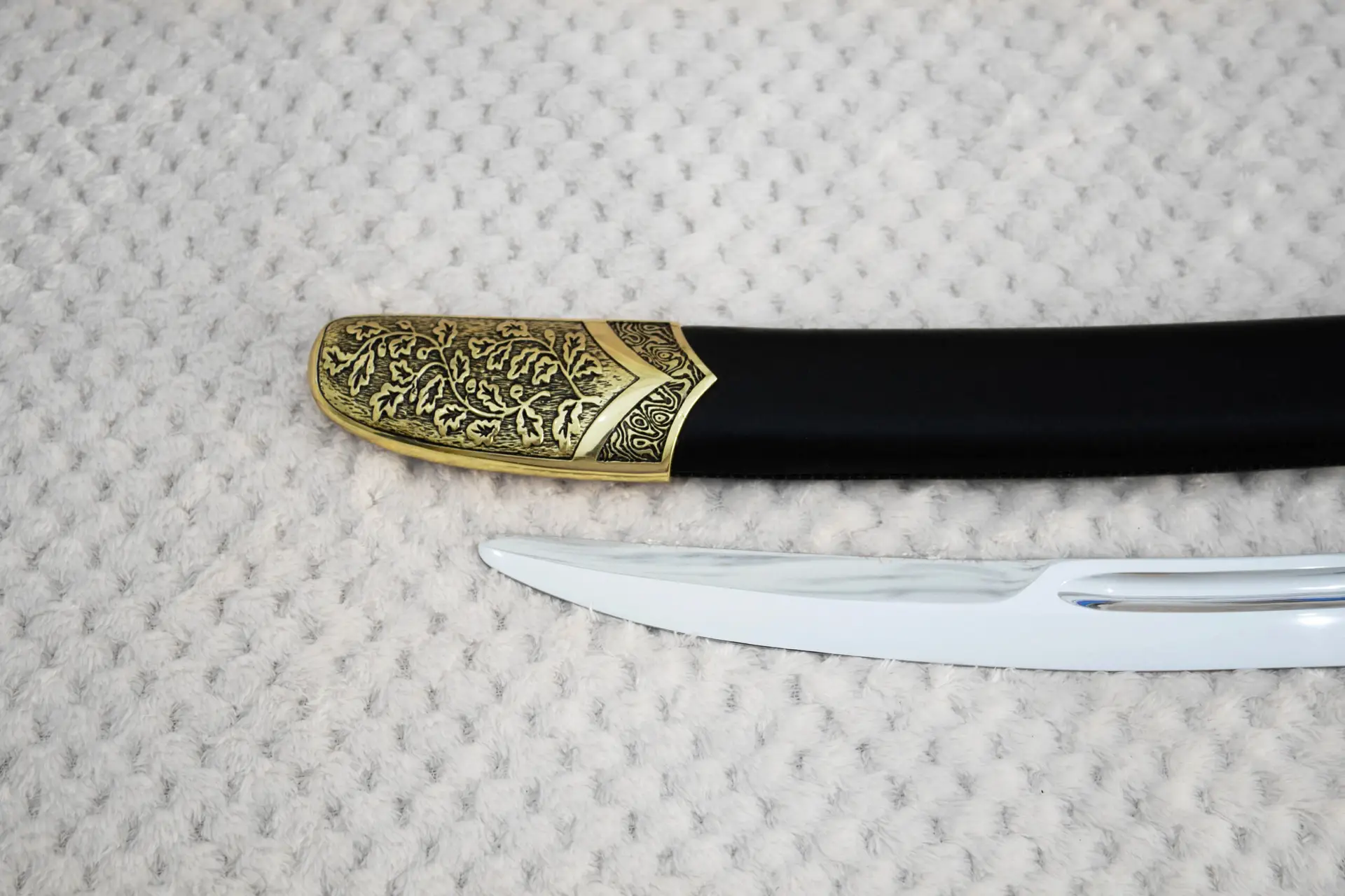 SiCh-Hetman saber blade tip beside the floral-patterned tip of its black scabbard