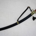 Sheathed SiCh-Souvenir saber in diagonal view with brown grip, decorated guard, carrying strap and tassel