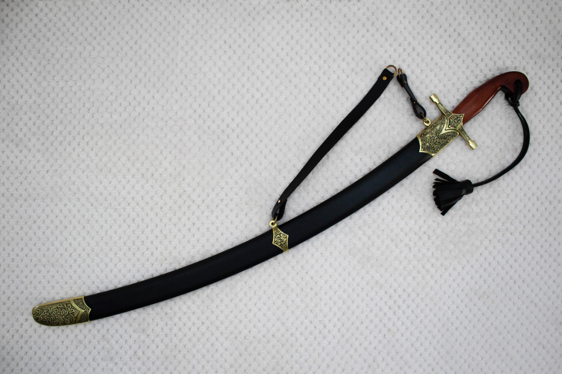 Sheathed SiCh-Souvenir saber in diagonal view with brown grip, decorated guard, carrying strap and tassel
