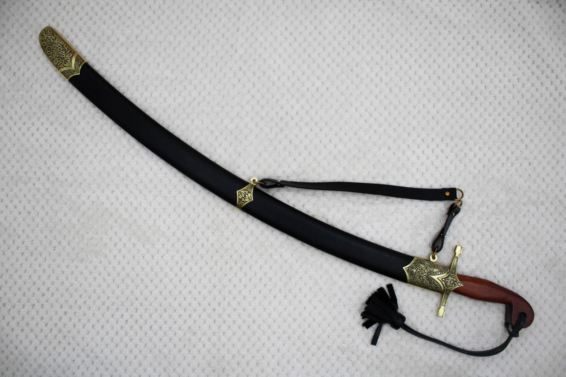 SiCh-Souvenir saber in a curved black scabbard with decorated tip and carrying strap, diagonal view