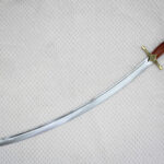 Unsheathed SiCh-Souvenir saber arranged diagonally with curved blade, reddish-brown grip and black tassel