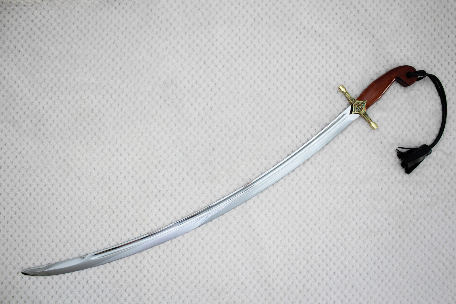 Unsheathed SiCh-Souvenir saber arranged diagonally with curved blade, reddish-brown grip and black tassel