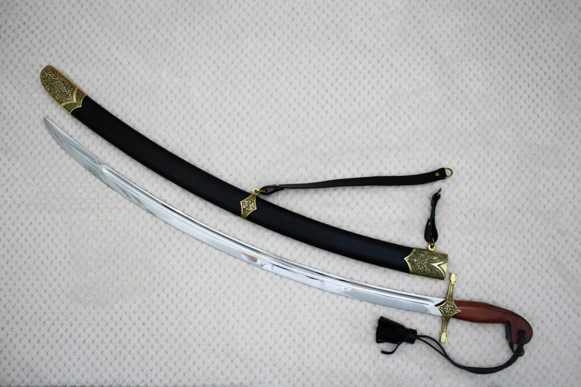 SiCh-Souvenir curved blade beside its black scabbard, with decorated scabbard tip and carrying strap
