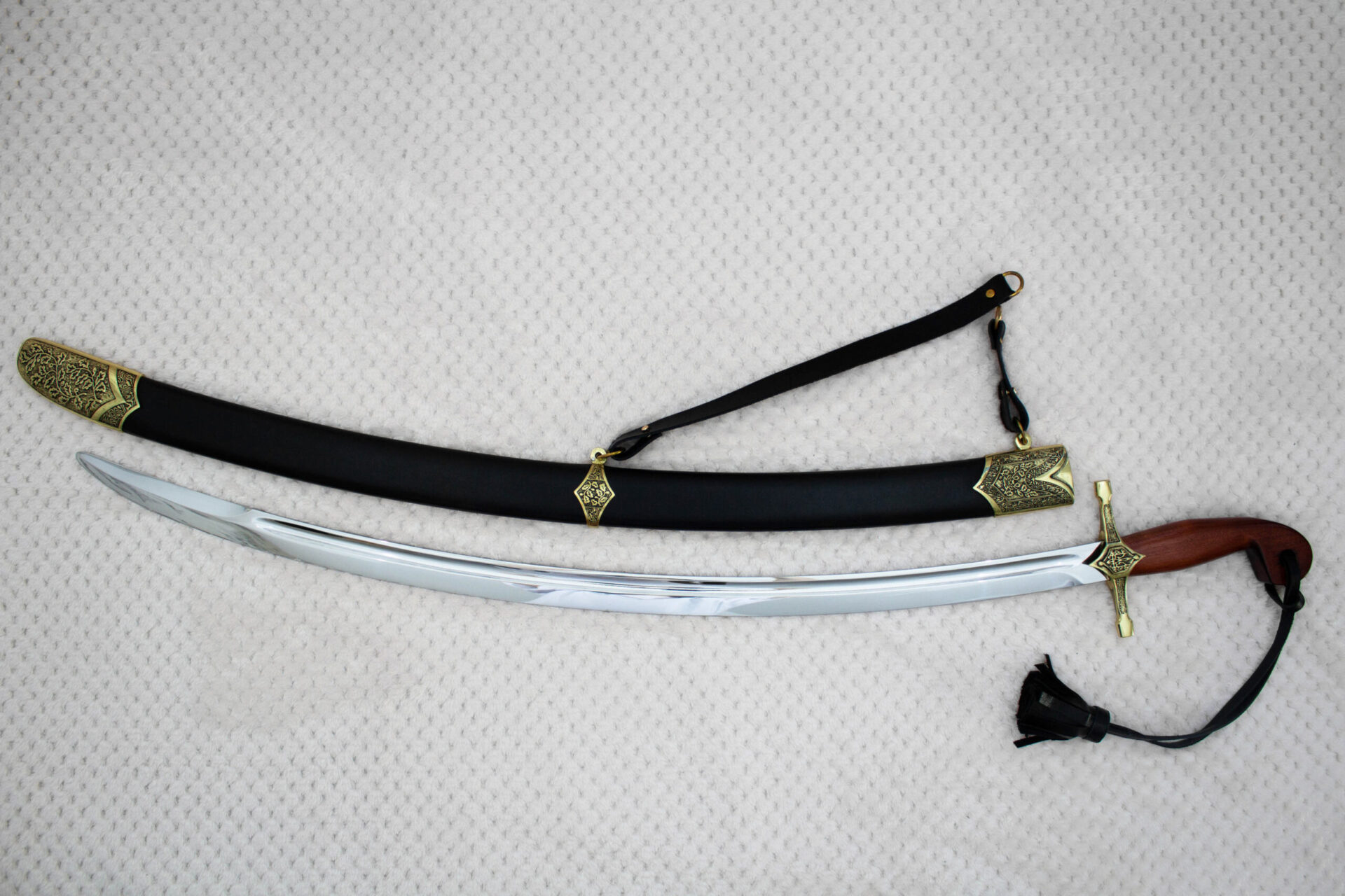Full side view of the unsheathed SiCh-Souvenir saber below its black scabbard with decorated fittings
