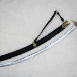 SiCh-Souvenir saber beside its black scabbard in diagonal view, with brown grip, carrying strap and tassel