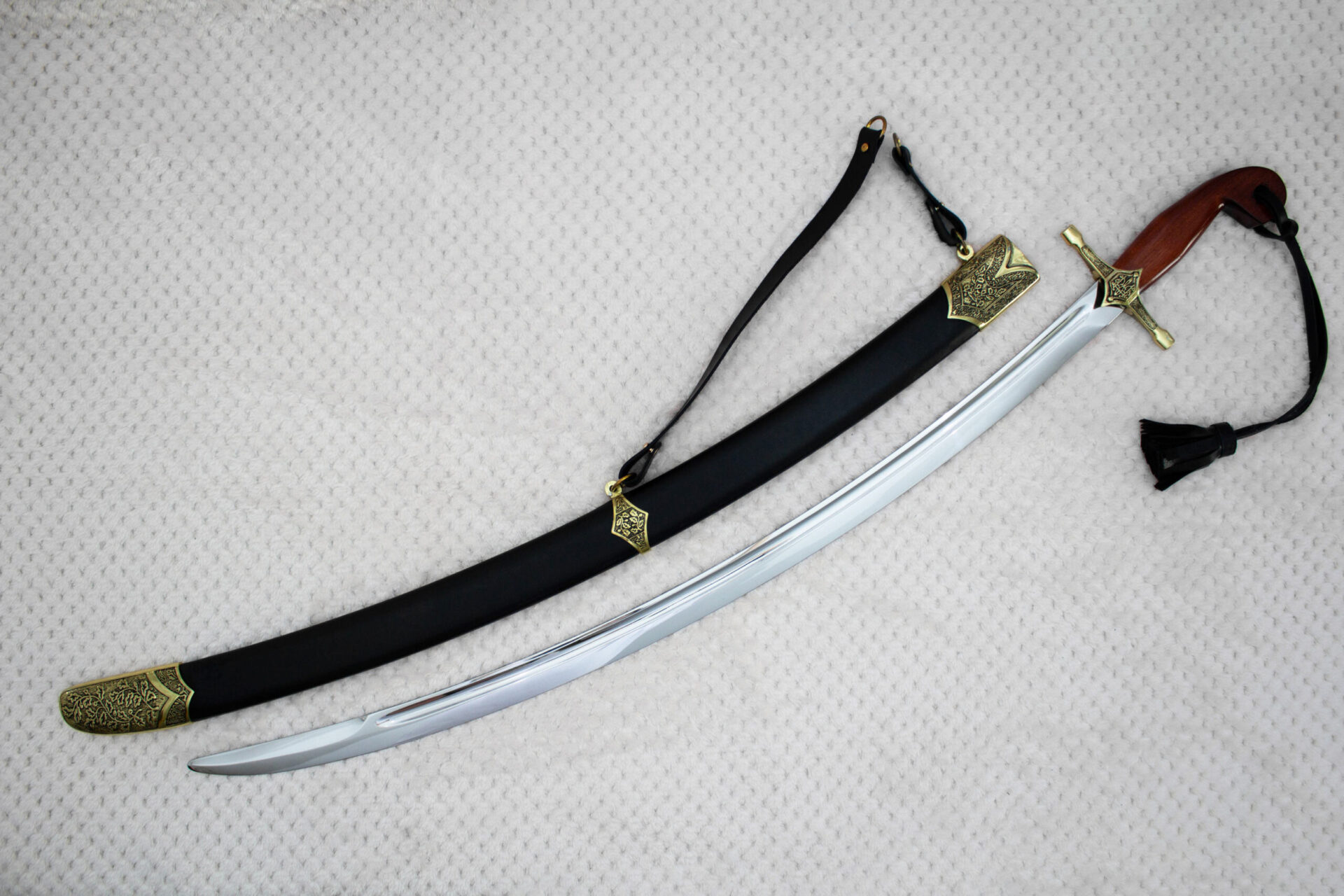 SiCh-Souvenir saber beside its black scabbard in diagonal view, with brown grip, carrying strap and tassel