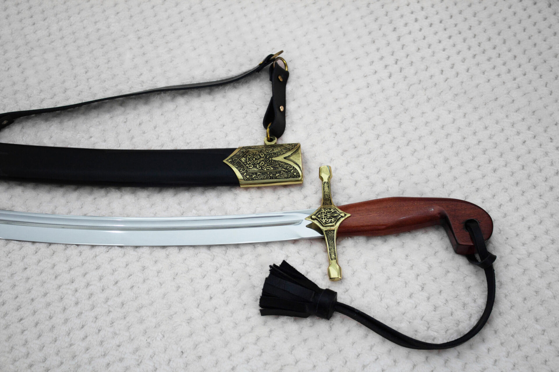 SiCh-Souvenir saber blade and brown hilt below a black scabbard with patterned mouth and carrying strap
