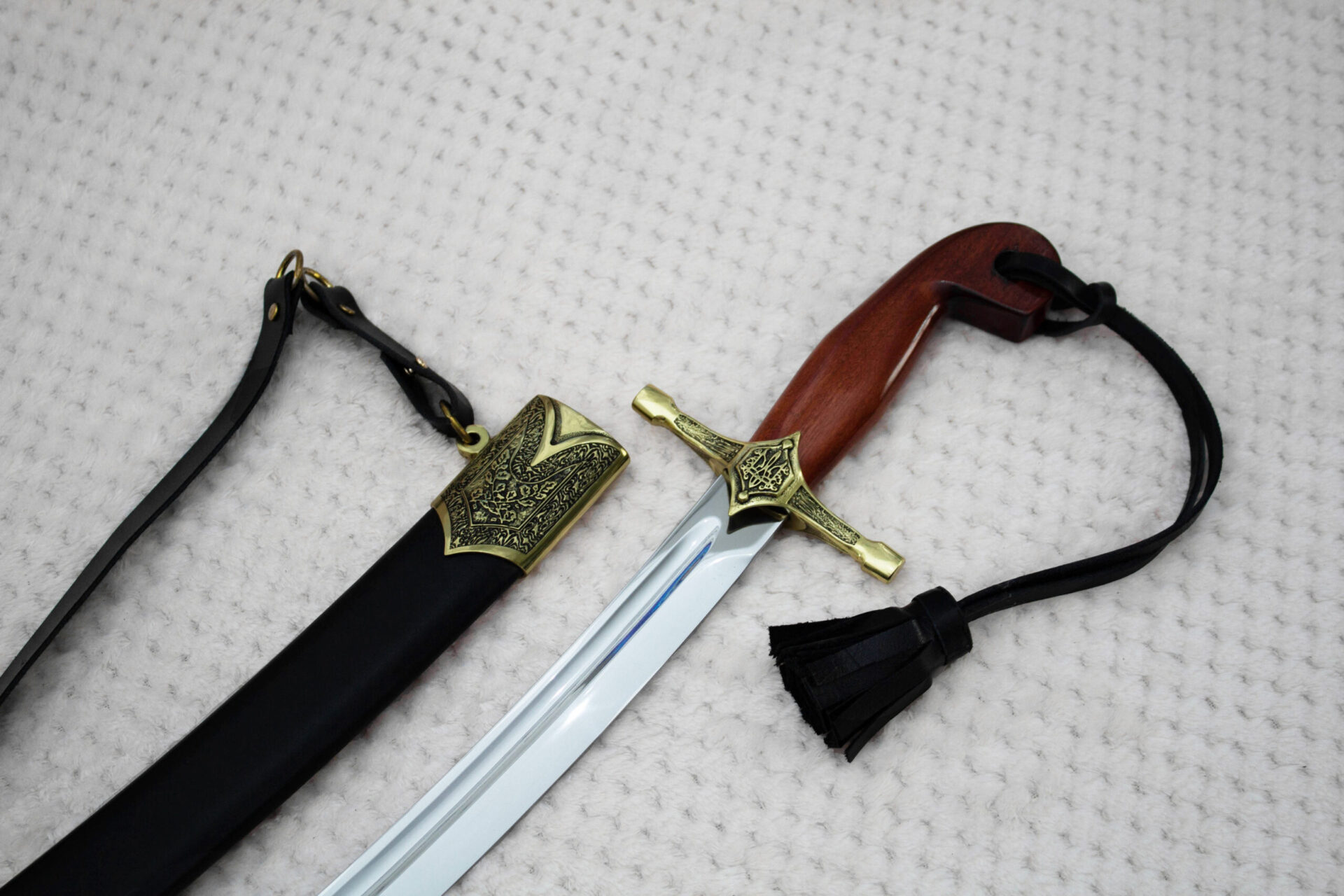 SiCh-Souvenir saber hilt beside its scabbard mouth, showing brown grip, ornamented guard and black straps