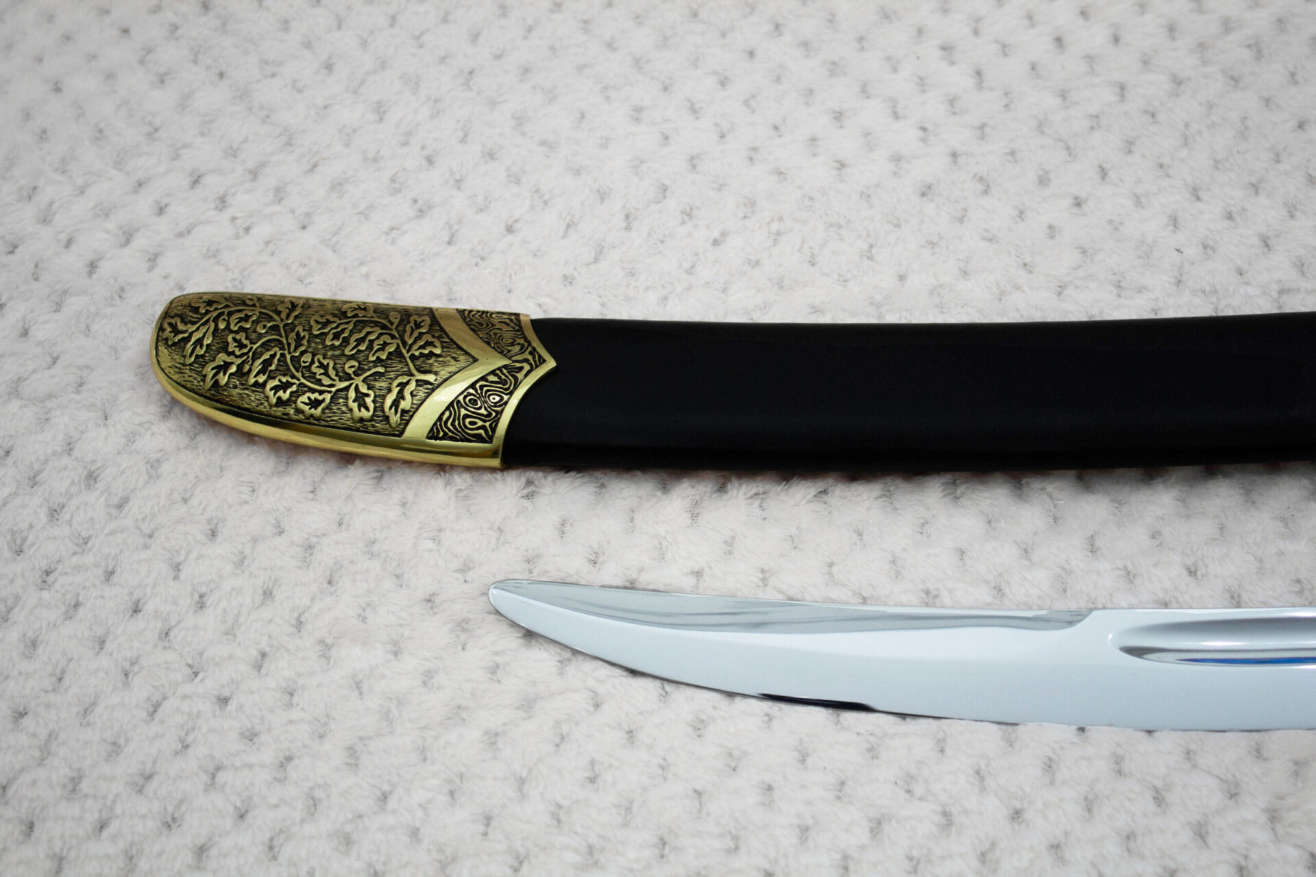 Close-up of the SiCh-Souvenir black scabbard tip with floral and spiral ornament