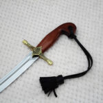 SiCh-Souvenir saber hilt and blade base with decorated guard, curved brown grip and black tassel strap