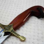 SiCh-Souvenir saber grip close-up with reddish-brown grain, trident-decorated guard and black tassel strap